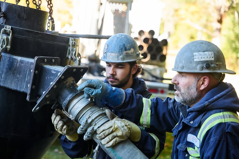 Main tendant un verre d’eau claire symbolisant un puits artésien  à Coaticook.