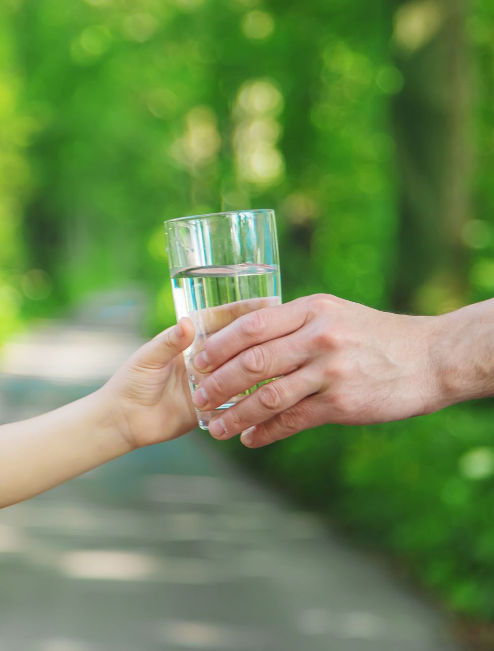 Main tendant un verre d’eau claire symbolisant un puits artésien  à La Sarre.